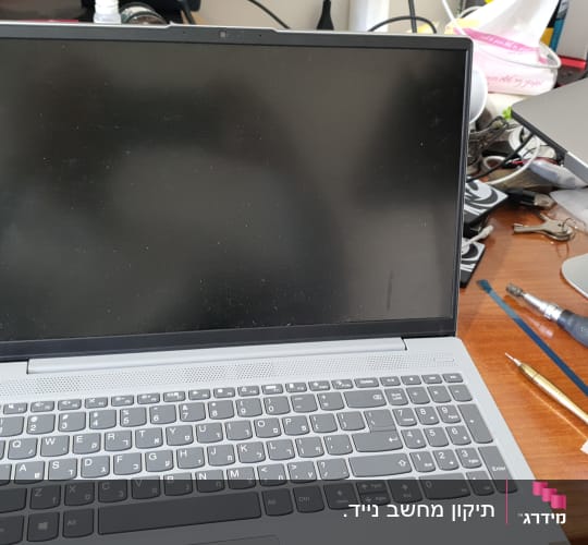 מחשב נייד עם מסך כבוי וכלי עבודה על שולחן